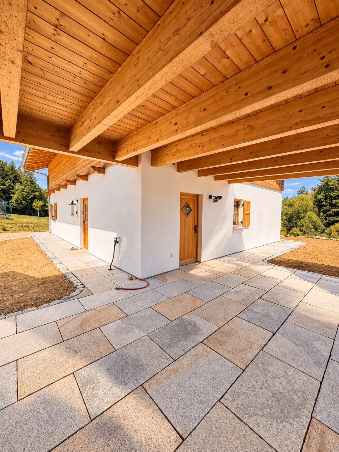 Überdachte, gepflasterte Terrasse an einem Haus